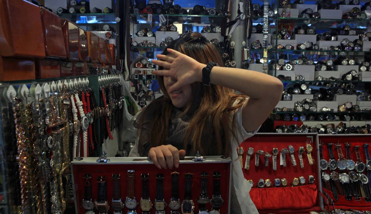 Una vendedora de relojes se tapa la cara en el Mercado de la Seda de Pekín