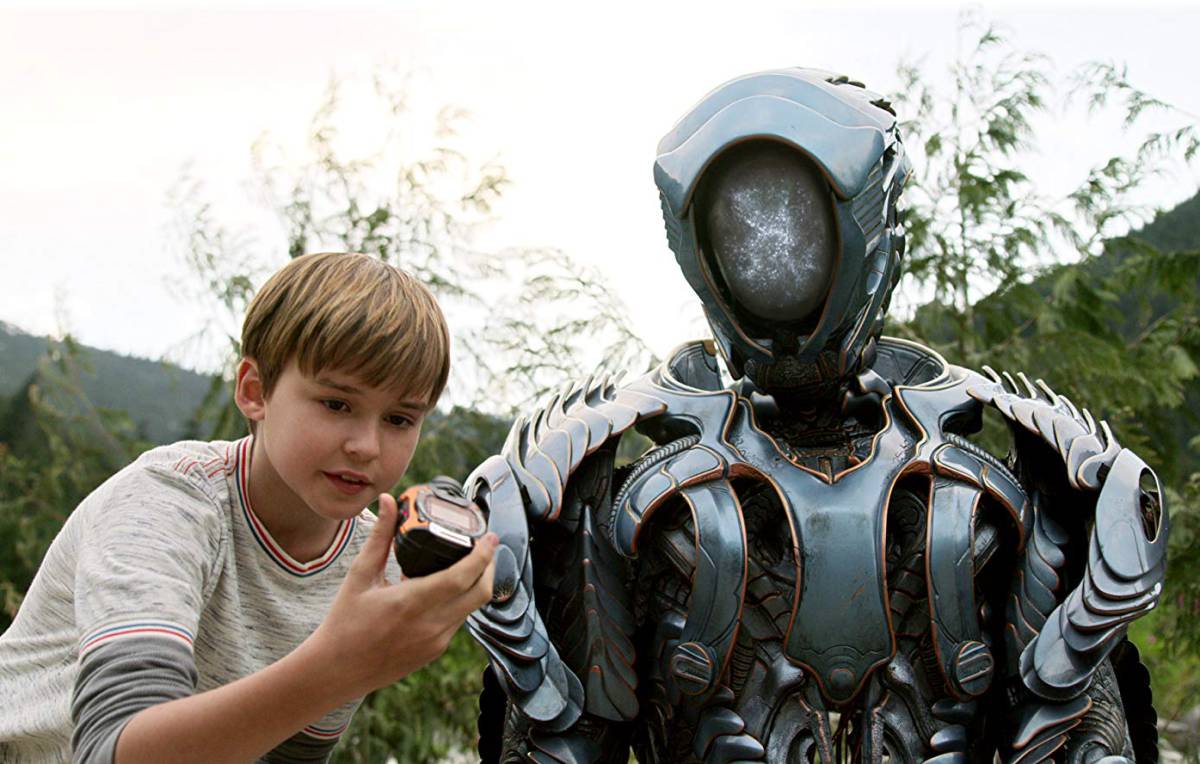 MaxwelL Jenkins como Will Robinson con inseparable robot en una escena del remake de 'Lost in Space' (2018)
